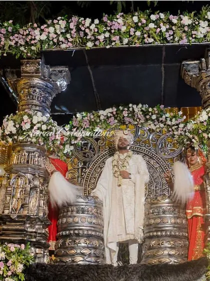 A spectacular groom entry on a massive, ornate silver chariot adorned with flowers. This kind of larger-than-life entrance ensures the groom's arrival is a major highlight of the wedding.