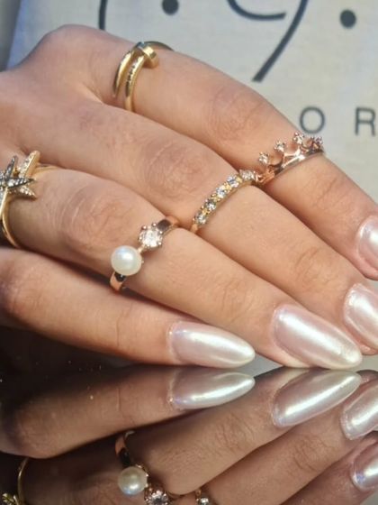 A side view of the glowing pearlescent stiletto nails, styled with an array of beautiful rings.