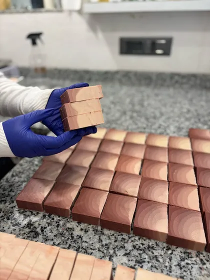 Holding up a stack of freshly cut soap bars. The natural color and texture of these bars come from the plant-based ingredients we use.