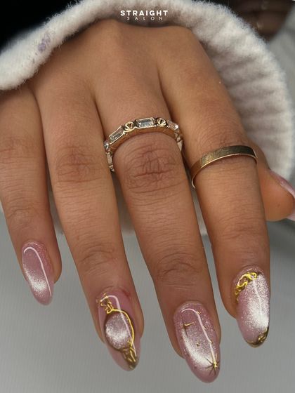 A soft pink cat-eye manicure with intricate, sculpted gold accents. The combination of the shimmering base and the metallic details is pure luxury.