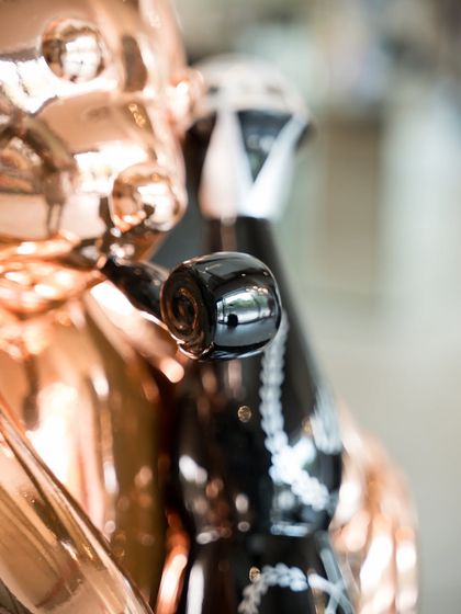 A detail shot of the "Let’s Party Teddy," highlighting the pacifier-like object in its mouth, a symbol of arrested development.