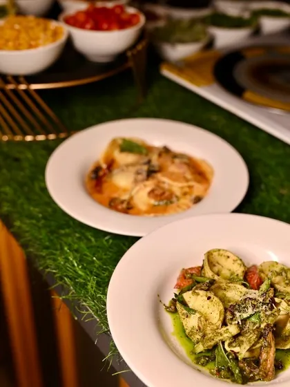 Two different pasta dishes prepared at our live station, one with a pesto sauce and the other with a classic tomato-based sauce, showing the variety we offer.