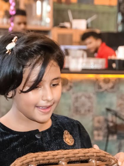 A candid shot of a young girl smiling as she looks into a basket during a party.