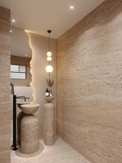 This powder room concept uses travertine stone to create a warm, earthy, and monolithic feel. The design features a sculptural pedestal sink and an organically shaped mirror, blending natural materials with modern forms.