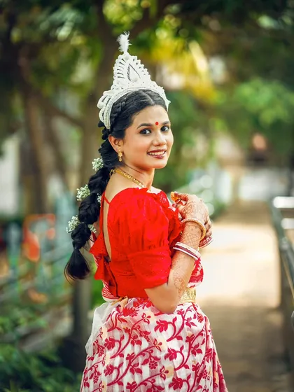 The bride looks back with a warm smile, her traditional braided hairstyle and beautiful saree creating a timeless portrait.
