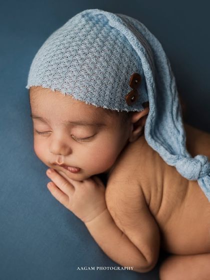 A bundle of joy in baby blue. This newborn is wearing an adorable knotted hat, adding a whimsical touch to this classic sleepy portrait.