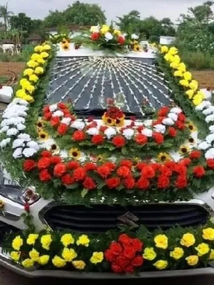 A traditional car decoration with heavy garlands of red, yellow, and white flowers covering the entire front of the car.
