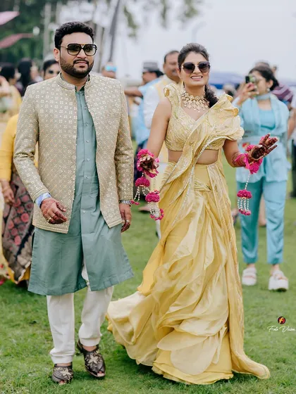 A stylish shot of the couple walking at their Goa Haldi ceremony, looking cool and chic in their sunglasses.