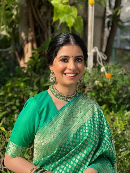 The client looking radiant and happy. The clean, center-parted bun with gajra is a graceful look for any wedding ceremony.