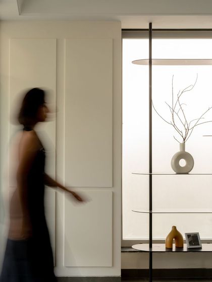 The minimalist metal shelving unit is set against a frosted glass window, allowing natural light to silhouette the decorative objects on display.