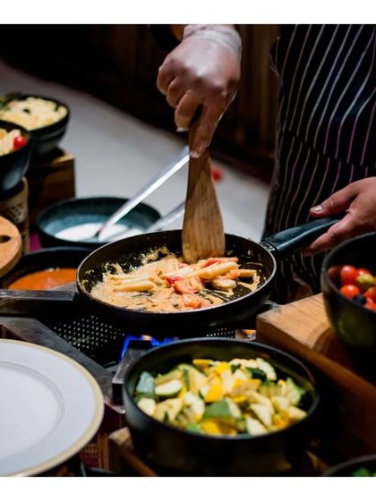 A chef prepares fresh pasta at a live ristorante station, tossing it in a creamy sauce with fresh vegetables. This interactive counter allows guests to customize their pasta, ensuring a perfectly tailored Italian dish.