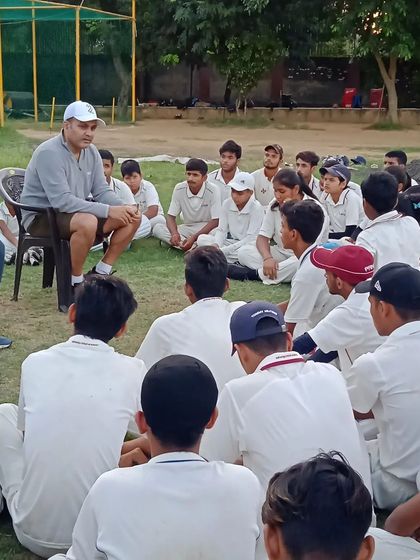 Seated informally on the field, our founder creates a comfortable environment for young players to learn and absorb lessons on cricket and life.
