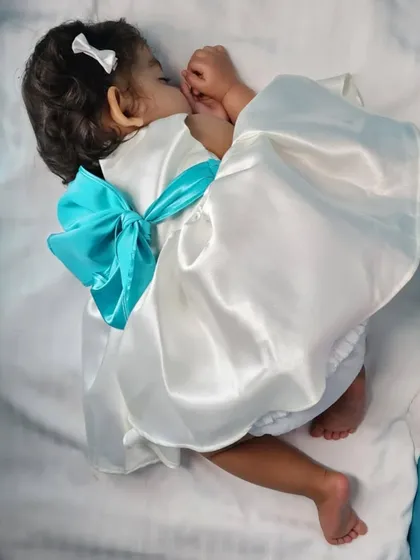 Even the littlest angels need a special dress. I designed this white satin infant gown with a big, beautiful bow, ensuring comfort for the baby and an adorable look for wedding photos.