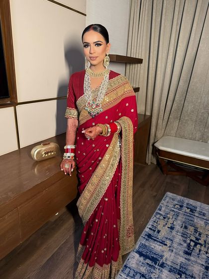 A stunning bride in a classic red Sabyasachi saree. The makeup features a bold smokey eye and a neutral lip, creating a powerful and regal look for her special day.