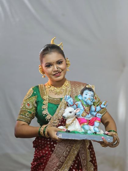 Holding a beautiful blue Ganpati idol, this model showcases the versatility of the red Nauvari look.