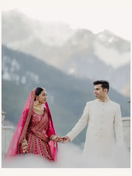 The couple holds hands, their figures framed by the snow and mountains. A beautiful, serene moment from their destination wedding.