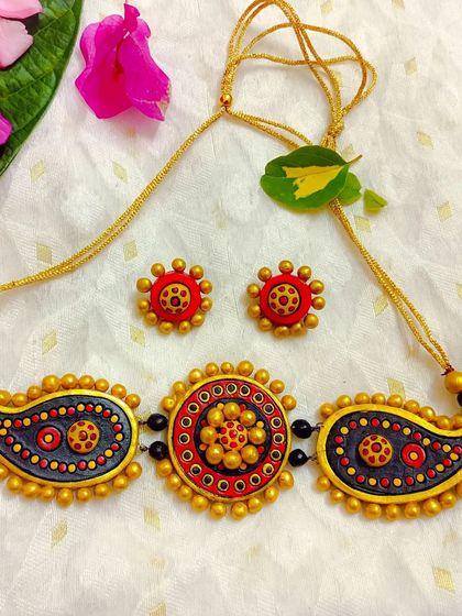 This stunning choker features a central mandala-style piece flanked by two paisley pendants. This version is in a classic red, black, and gray combination.