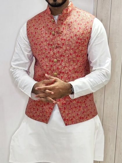A close-up of a red and gold patterned Nehru jacket paired with a classic white kurta, a perfect combination for any celebration.