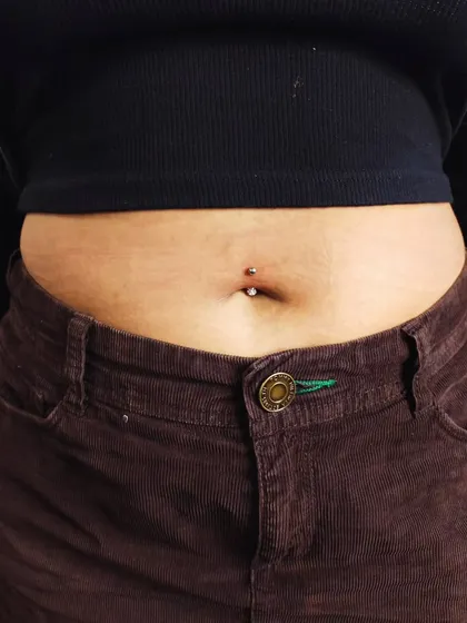 The final result of a standard navel piercing, shown on the client. This body piercing is a popular way to accessorize and express personal style.