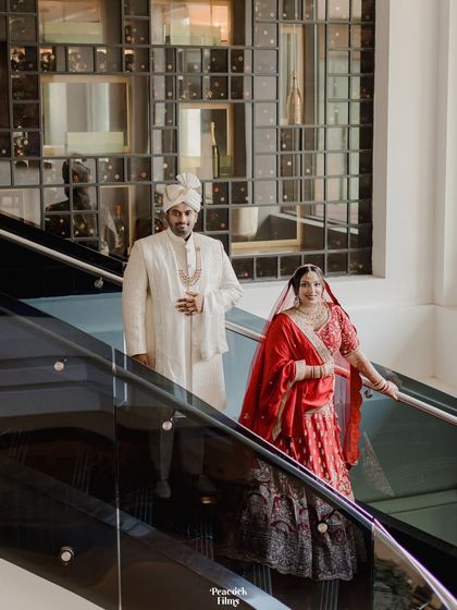 The couple poses on a modern, sleek staircase, their traditional attire creating a beautiful contrast with the contemporary architecture.