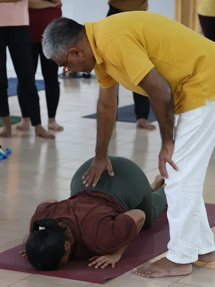 A student receives an adjustment in Ashtanga Namaskara, the eight limbed pose. This personal guidance helps in building strength and proper form.
