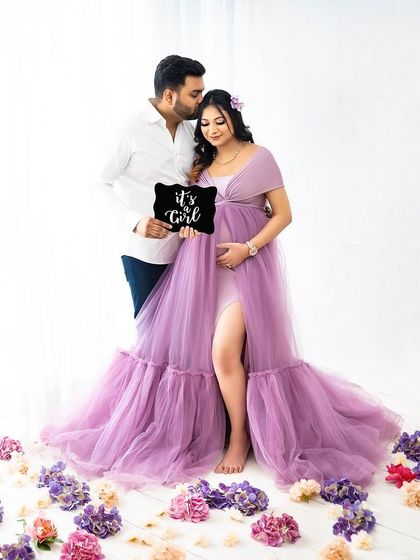 A beautiful full-length portrait announcing "It's a Girl!" The lilac gown and scattered flowers create a soft and dreamy atmosphere.