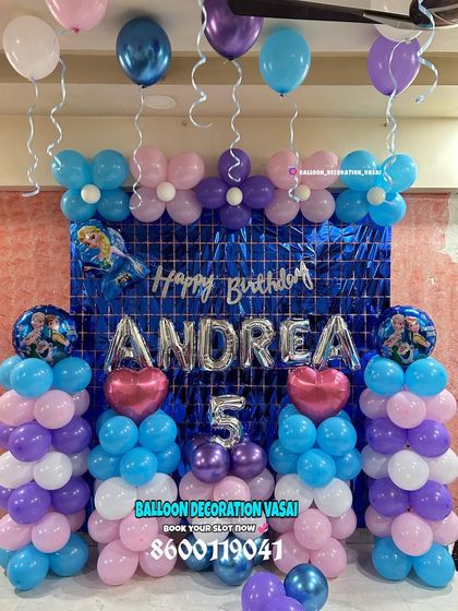 A Frozen-themed decoration for Andrea's 5th birthday. This setup features balloon pillars, a blue shimmer curtain, and a foil name banner.