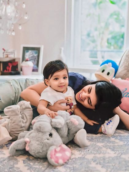 Lying on a bed surrounded by stuffed animals, this mother and child share a happy, relaxed moment. It’s a perfect example of a candid in-home family photoshoot.