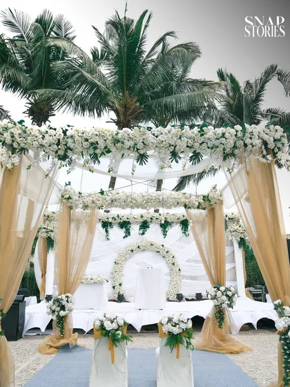 A beautiful view of an outdoor Christian wedding setup, with white floral arrangements and palm trees. We also specialize in capturing the decor and ambiance of your venue.