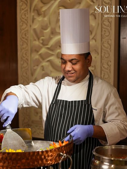 A smiling chef prepares a dish at a live Tawa station, showcasing the joy and passion our team brings to their craft. We believe in service with a smile.