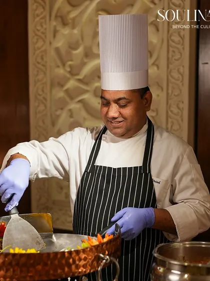 A smiling chef prepares a dish at a live Tawa station, showcasing the joy and passion our team brings to their craft. We believe in service with a smile.