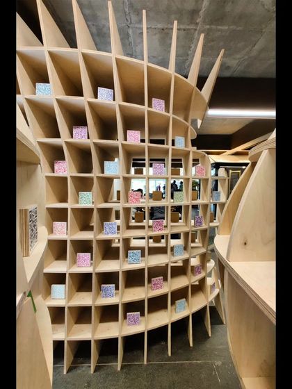 An interior view of the curved 'Stradata' folly, showing how the stacked layers of plywood create a dynamic, flowing space. The design plays with perspective and form, inviting people to walk through and experience its plasticity.