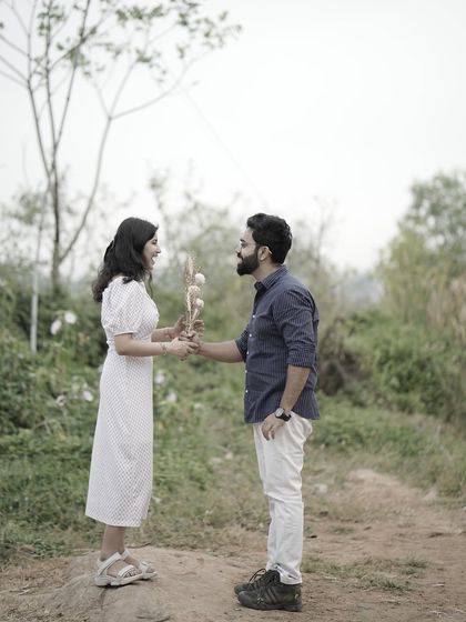 A sweet and simple shot of the groom offering a bouquet of dried flowers to the bride in a rustic, outdoor setting.
