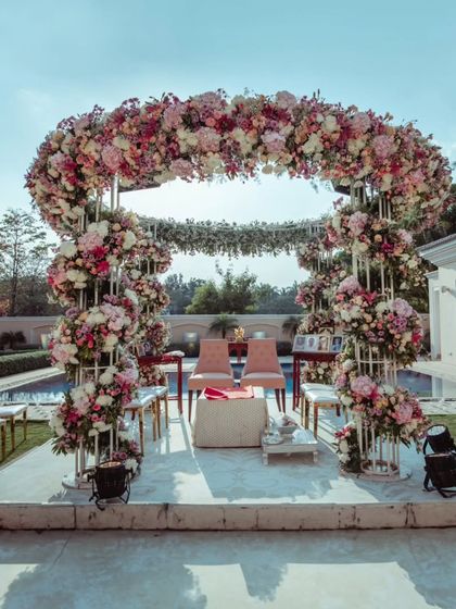 An intimate and elegant mandap for a home wedding, proving that you don't need a palace to have a fairytale ceremony. The poolside setup is adorned with a beautiful arch of pink and white flowers.