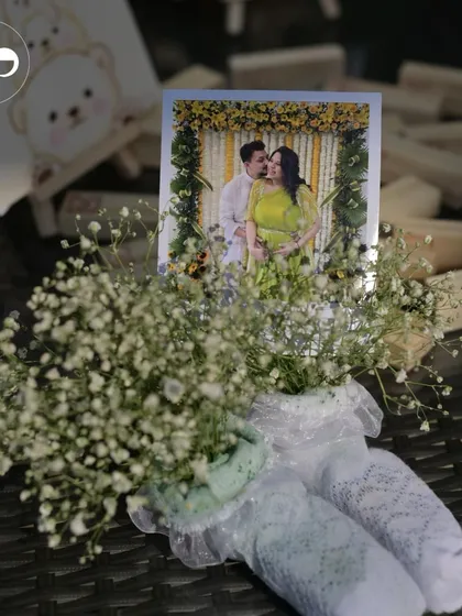 A centerpiece detail combining a guest's photo with fresh baby's breath in a pair of baby socks. This is a perfect example of a small, personalized touch that makes a big impact.