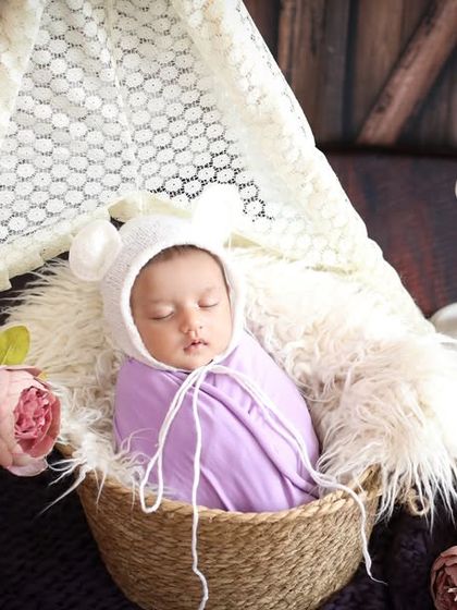 Nestled in a basket surrounded by flowers and candlelight, this baby is the picture of serenity. The lace tent adds a touch of dreamy elegance to the scene.