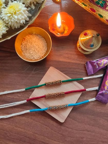 A set of simple and elegant rakhis made with thread and golden beads. These are available in green, red, and blue.