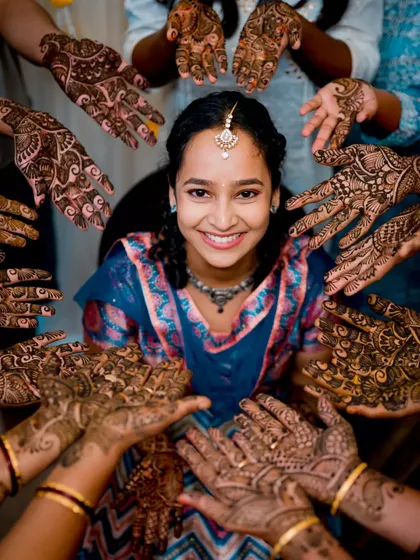 The intricate beauty of Mehendi deserves a special focus. We love finding creative ways to photograph this tradition, like this shot that frames the bride's joyful smile with the hands of her loved ones.