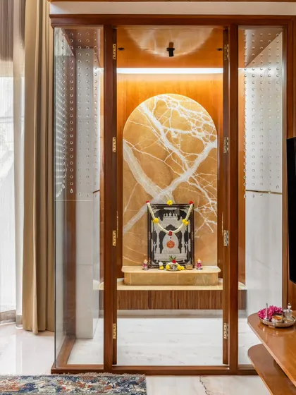 We integrated this tranquil pooja room into the main living area of the Avani Residence. Encased in glass and wood, the space features a monolithic onyx stone backdrop illuminated by a skylight, creating a serene and spiritual focal point.