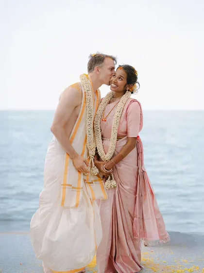 A sweet kiss on the cheek by the sea. This joyful portrait of Bhavana and Michael captures the happiness and love of their wedding day, blending cultures and hearts.