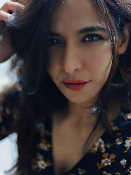 A close-up portrait that captures a playful and confident expression. The way she runs her hand through her hair adds a natural, unposed feel, while the tight framing on her face and bright eyes makes the image instantly engaging.