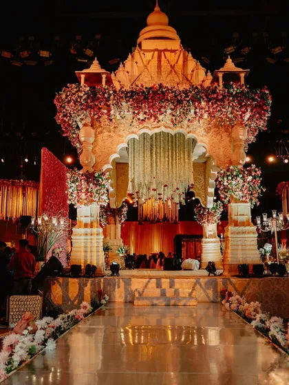 A wide shot of the temple mandap with its reflective aisle, capturing the grandeur of the structure and the elegance of the overall wedding setup.