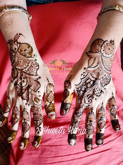 Another example of a beautiful Arabic mehendi design. This pattern features prominent peacock and paisley motifs connected by delicate vines that flow from the fingers to the wrist.