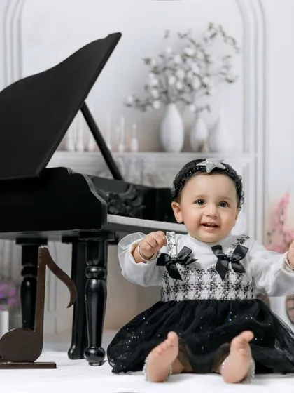 In a world full of grown-ups, be a kid who sees magic everywhere! A happy girl plays the piano in our elegant white studio.
