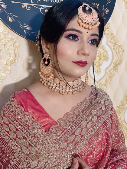 An elegant look for a wedding guest. The makeup features a sharp winged liner and pink eyeshadow, paired with beautiful peach-colored jewelry.