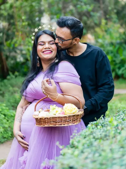 A sweet kiss for the glowing mom-to-be. The flower basket and starry crown add a whimsical, fairytale touch to this garden maternity shoot.