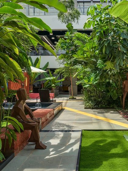 A pathway through the SAP Labs office courtyard, featuring custom-designed sculptural seating and lush greenery. The space is designed to encourage movement, informal meetings, and moments of pause during the workday.