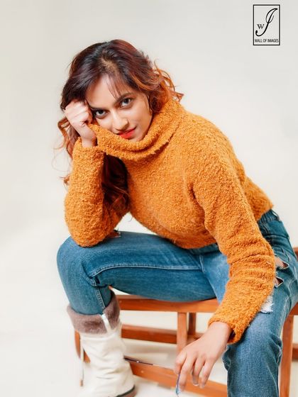 A cozy and expressive studio portrait for a winter-themed shoot, featuring a textured sweater and ripped jeans.