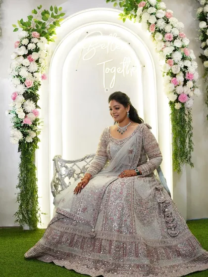 A beautiful portrait of the bride at her sangeet. The soft, elegant makeup and stunning silver lehenga create a look of pure sophistication against a romantic floral arch.