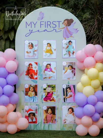 A heartwarming 'My First Year' photo display from a fairy-themed party. This personalized board, framed by pastel balloons, showcases the baby's monthly milestones, adding a deeply personal touch to the celebration.